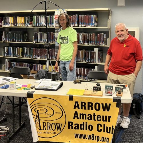 Two hams standing behind a table demonstrating amateur radio.