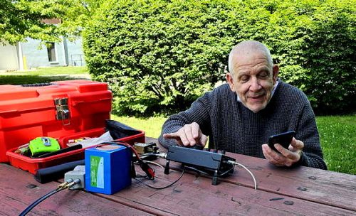 Man sitting in front of a radio on a picnic table.